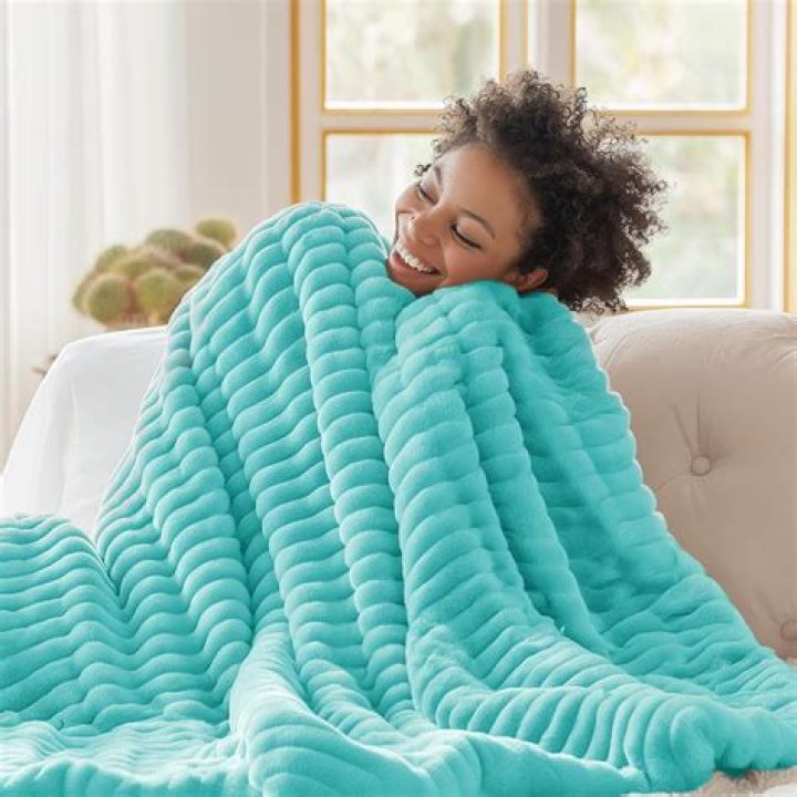 Woman on sofa with Bedsure Light Grey Fleece Blanket for Couch